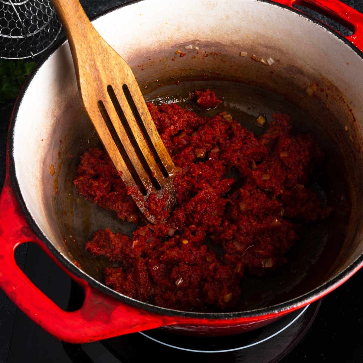 A thick paste of 'nduja, tomato paste, shallot and chili in a pot