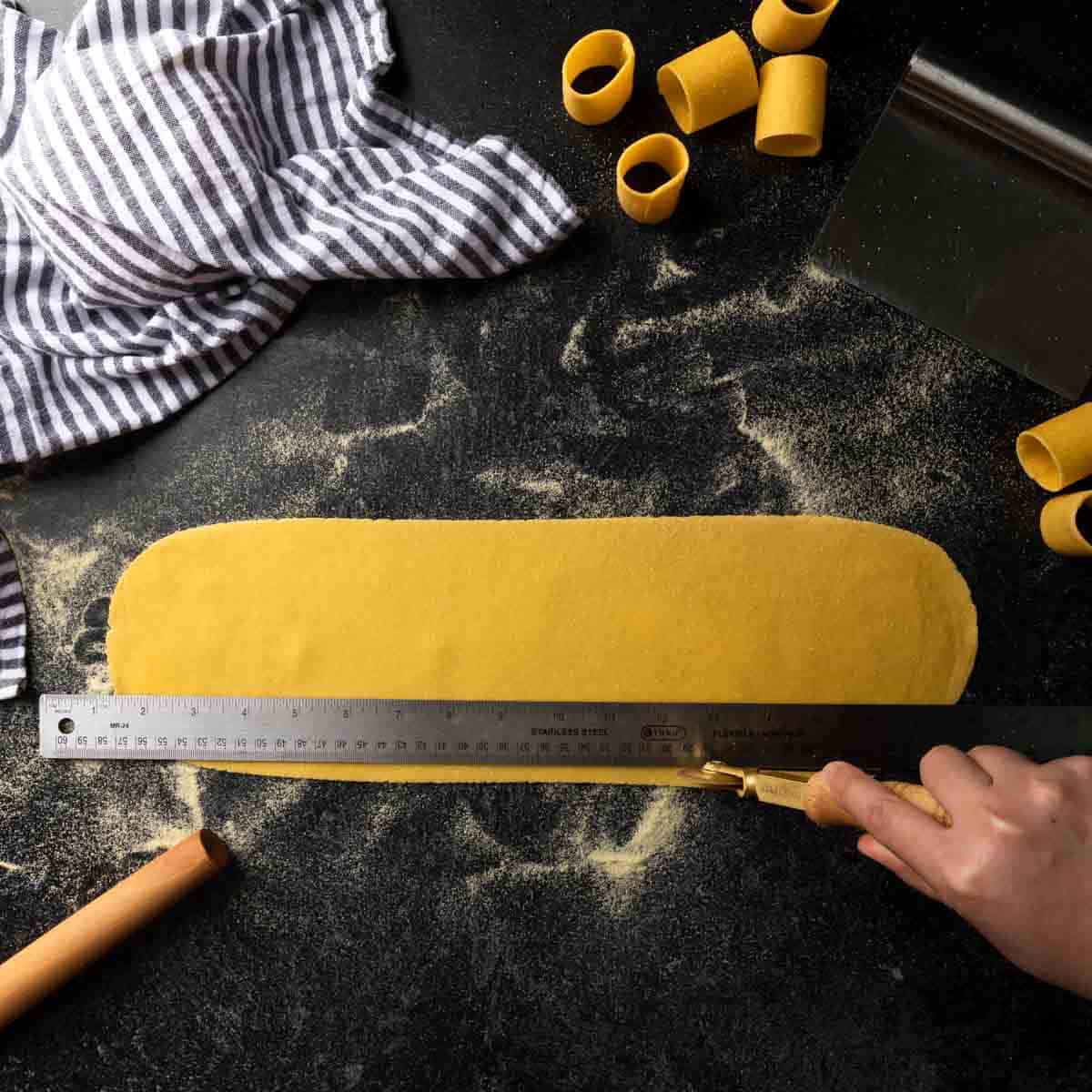 Using a brass pasta wheel and ruler to square a sheet of pasta dough