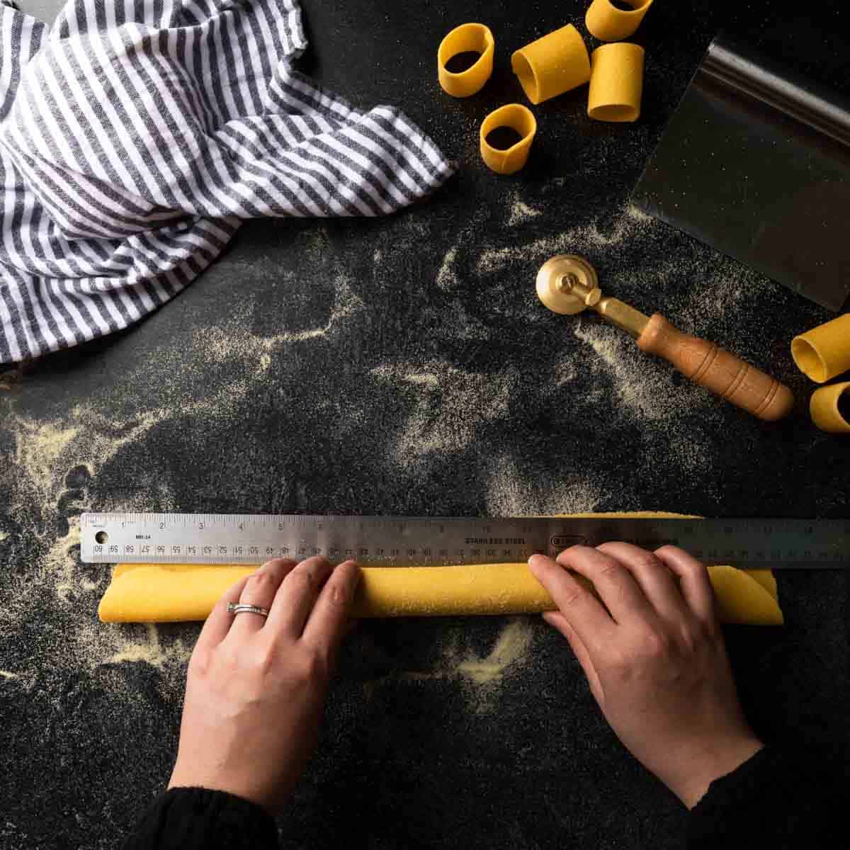 Rolling a sheet of pasta dough around a mini rolling pin