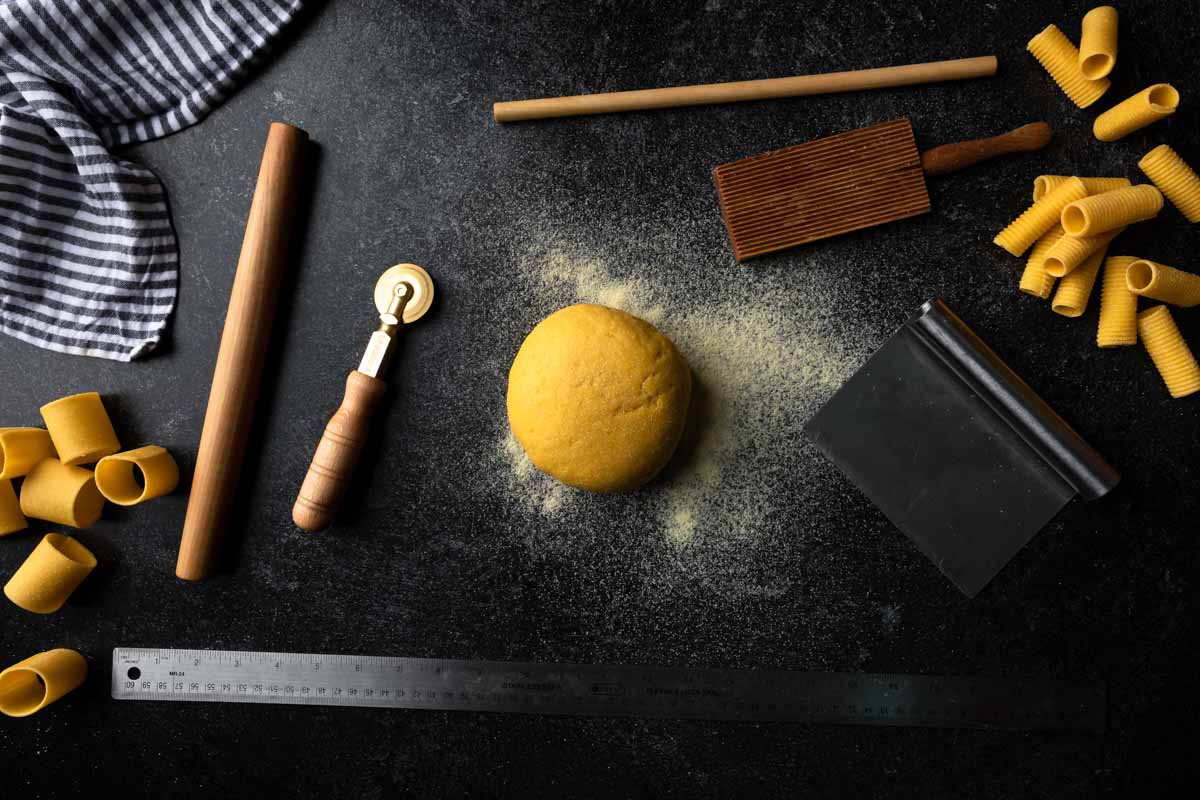 A picture of a ball of pasta dough and pasta making tools