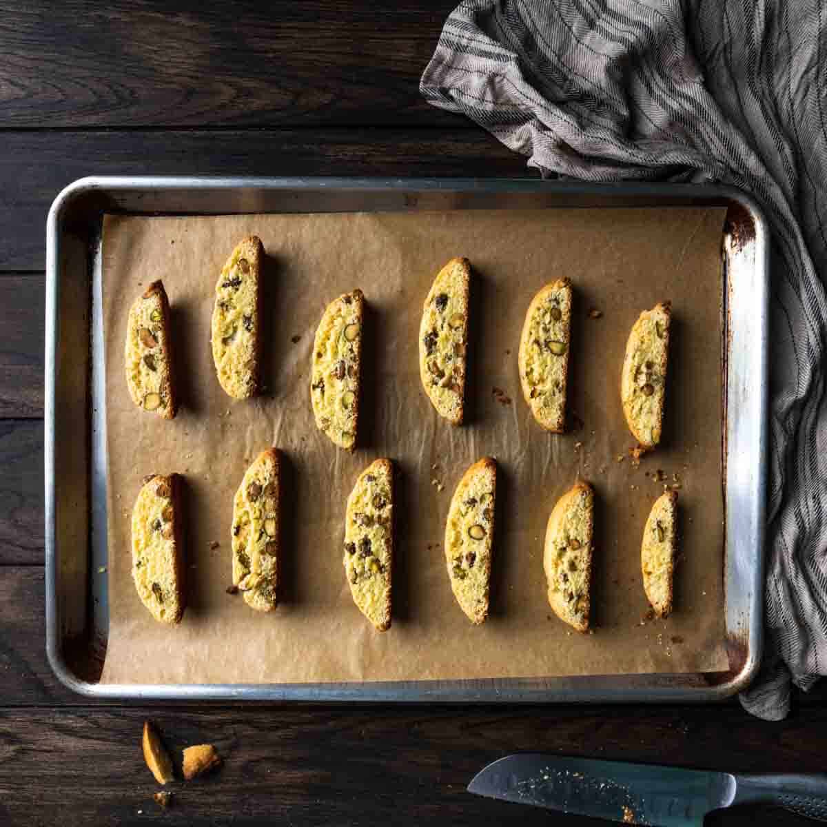Cut pistachio biscotti cookies arranged on a baking sheet
