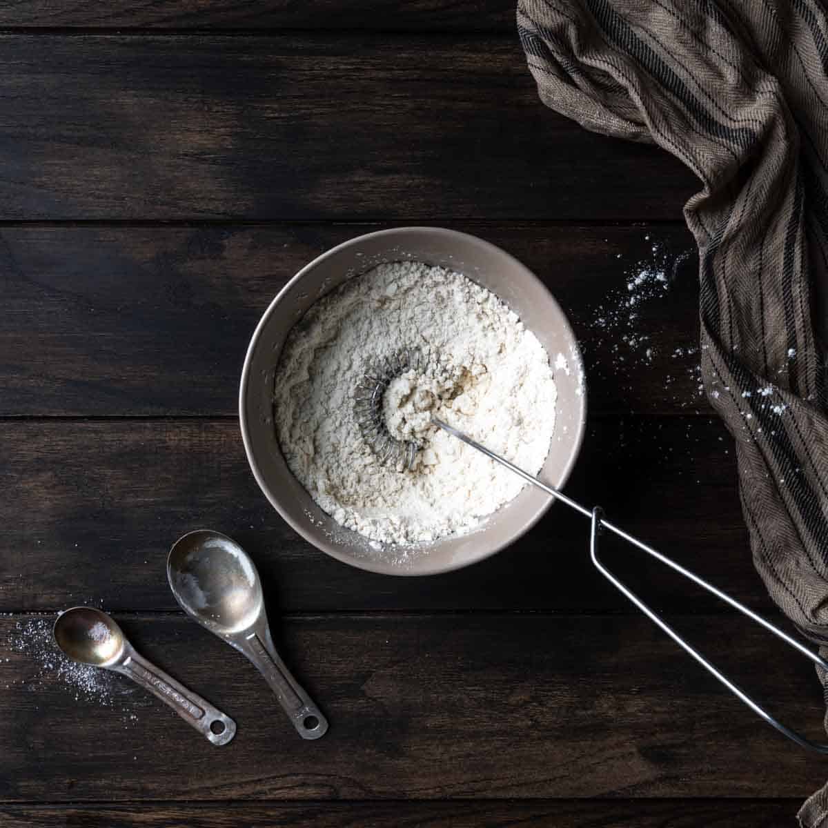 A small bowl with dry ingredients and a whisk