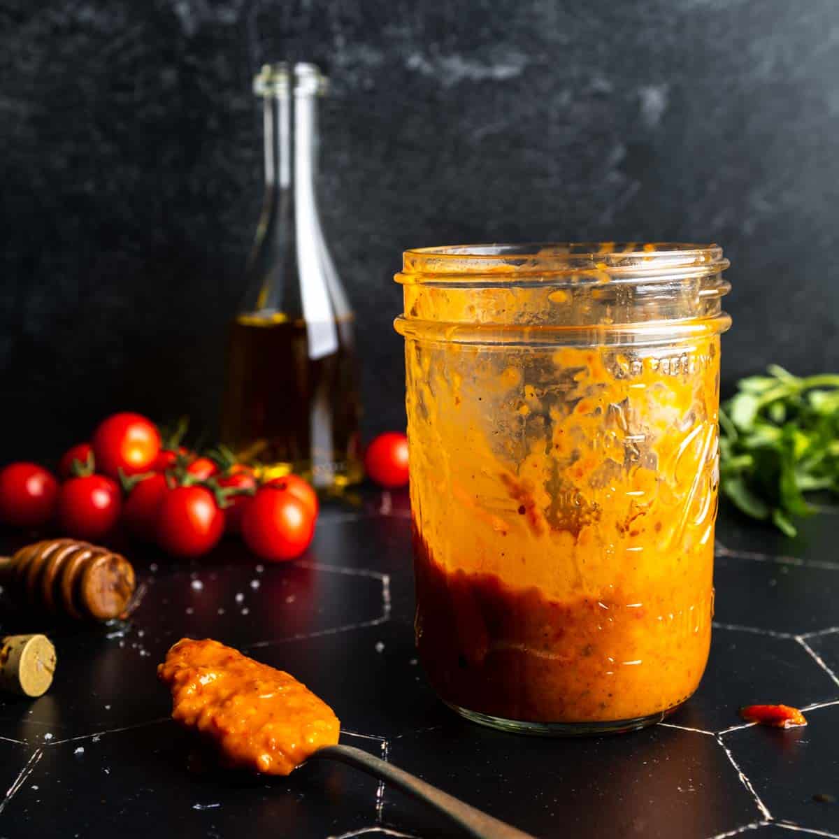 Finished roasted tomato vinaigrette in a jar and on a spoon