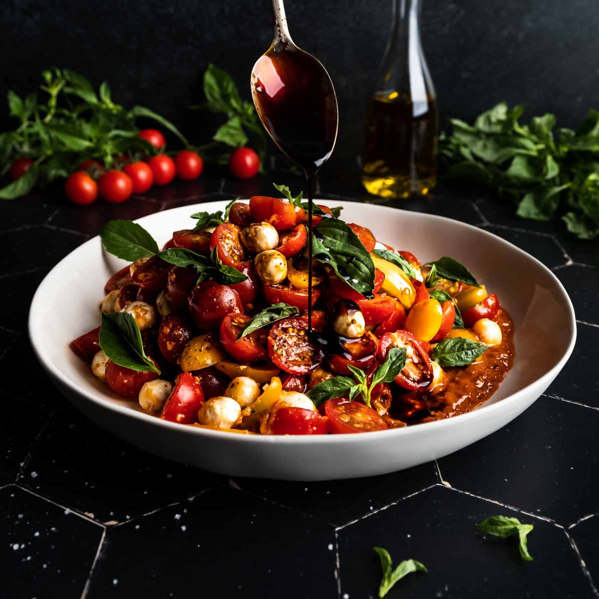 Drizzling balsamic glaze over the cherry tomato caprese salad