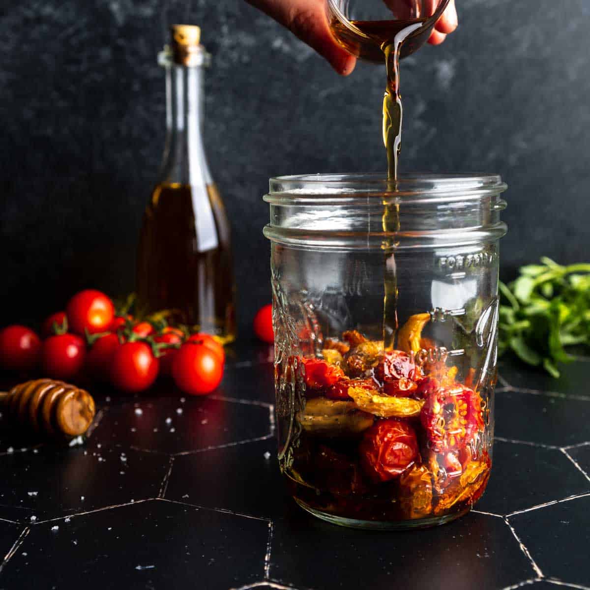 Pouring white balsamic vinegar over a jar of roasted tomatoes
