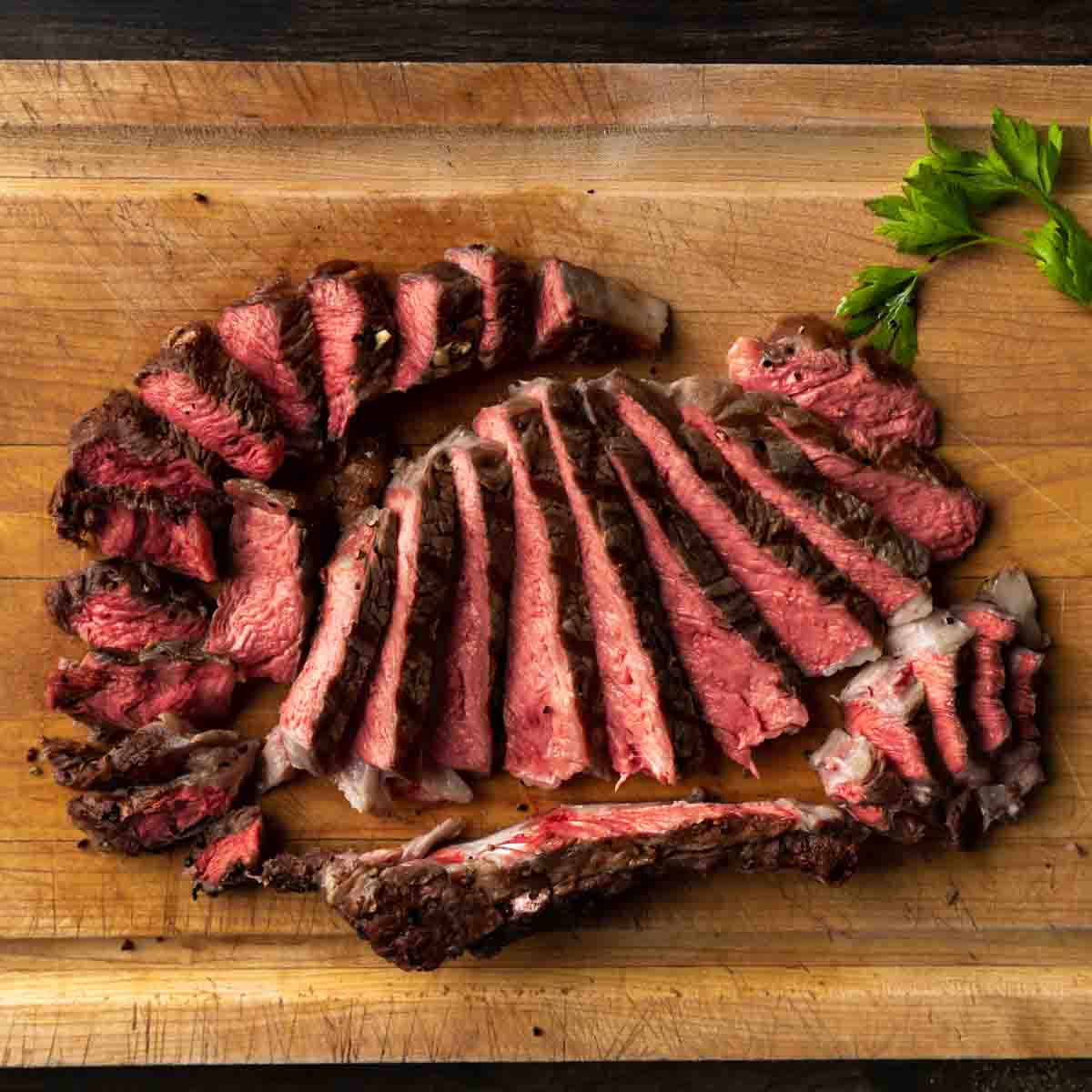 A carved and sliced ribeye steak on a cutting board