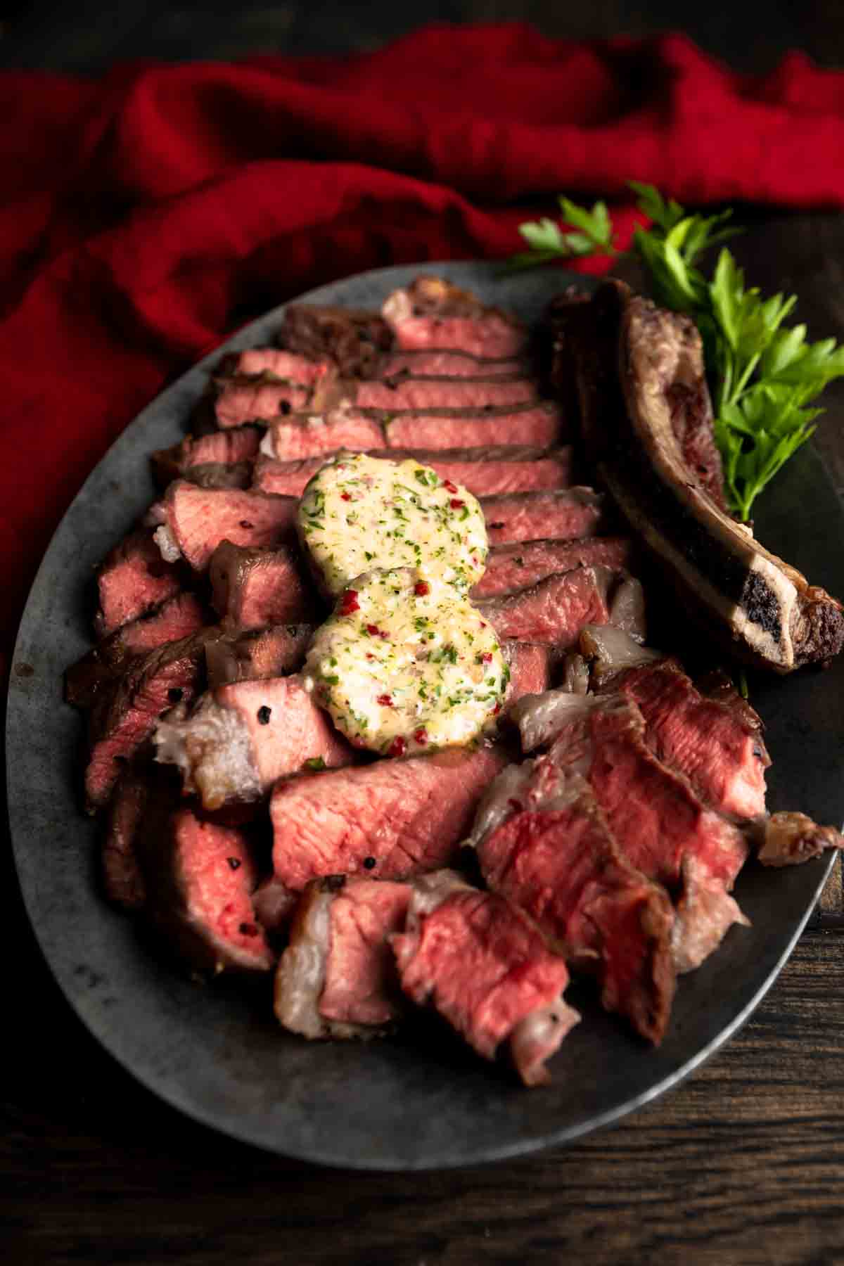 A medium rare ribeye steak topped with chimichurri butter