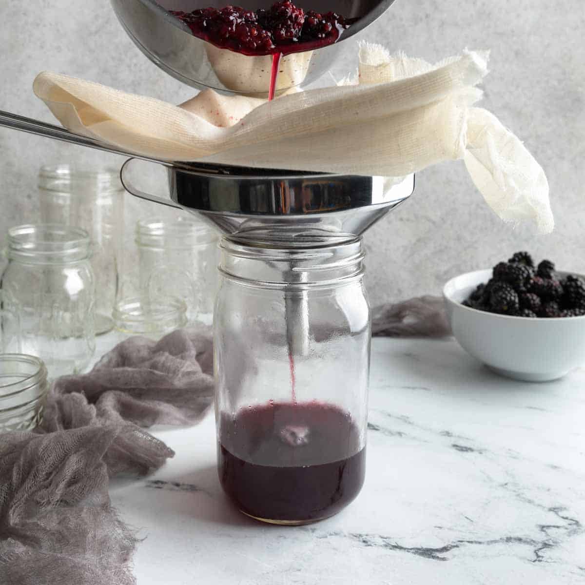 Pouring blackberry syrup through cheesecloth and a fine mesh strainer