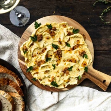 A circular butter board with pickled mustard seeds, parsley and spicy honey.