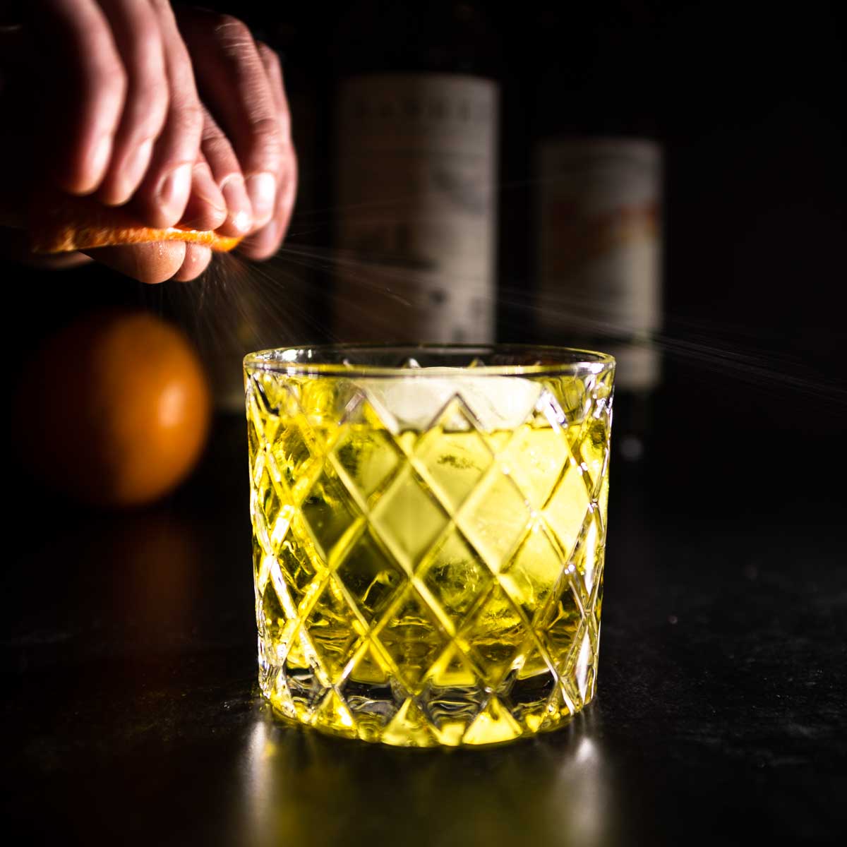 Expressing orange oils over a negroni cocktail