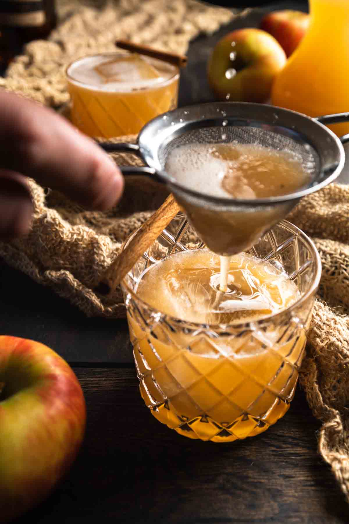 Straining an apple cider cocktail into the glass