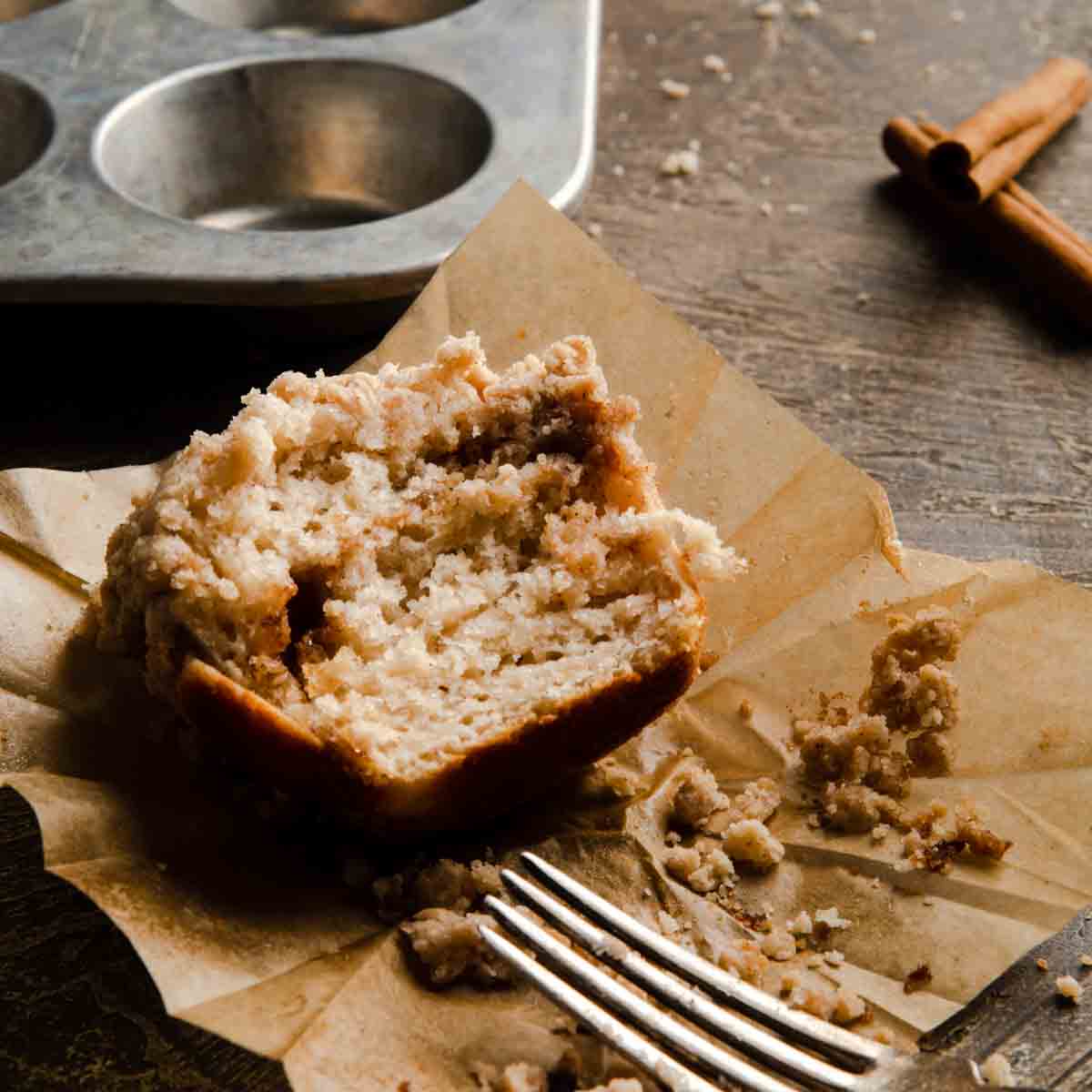 A freshly baked muffin on a parchment liner with a fork