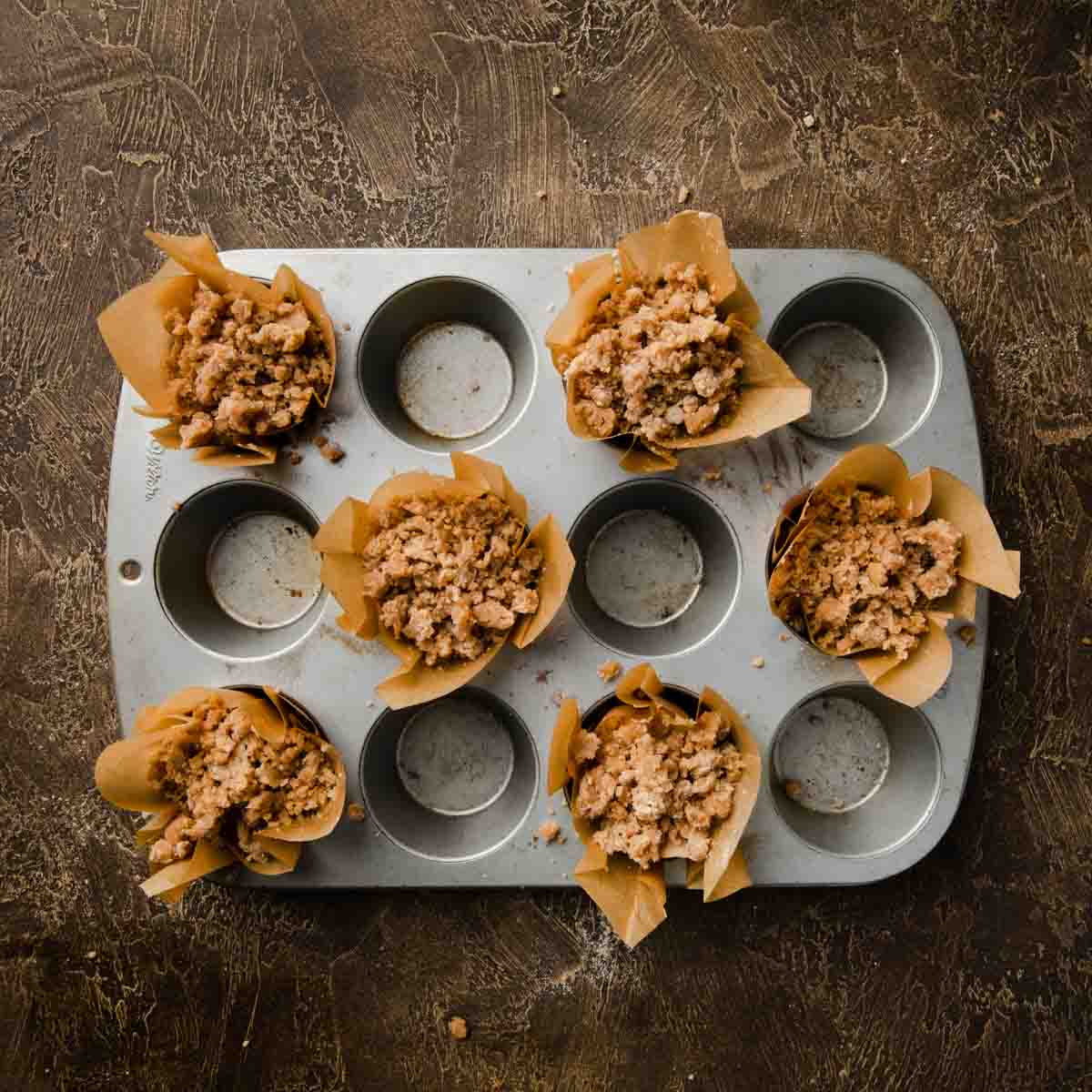 Every other muffin tin space filled with cinnamon streusel topped muffin batter