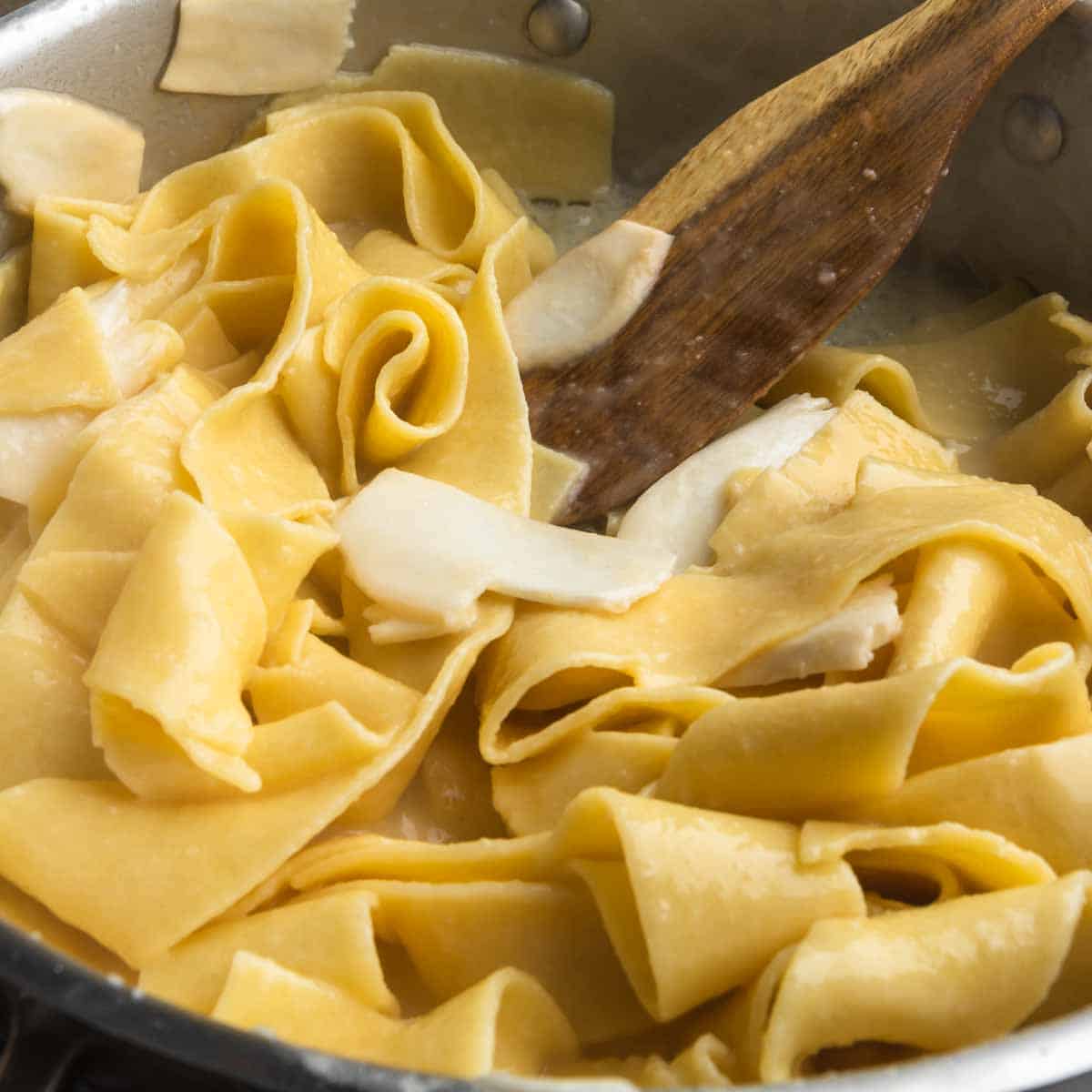 Stirring the pappardelle pasta into the pan sauce