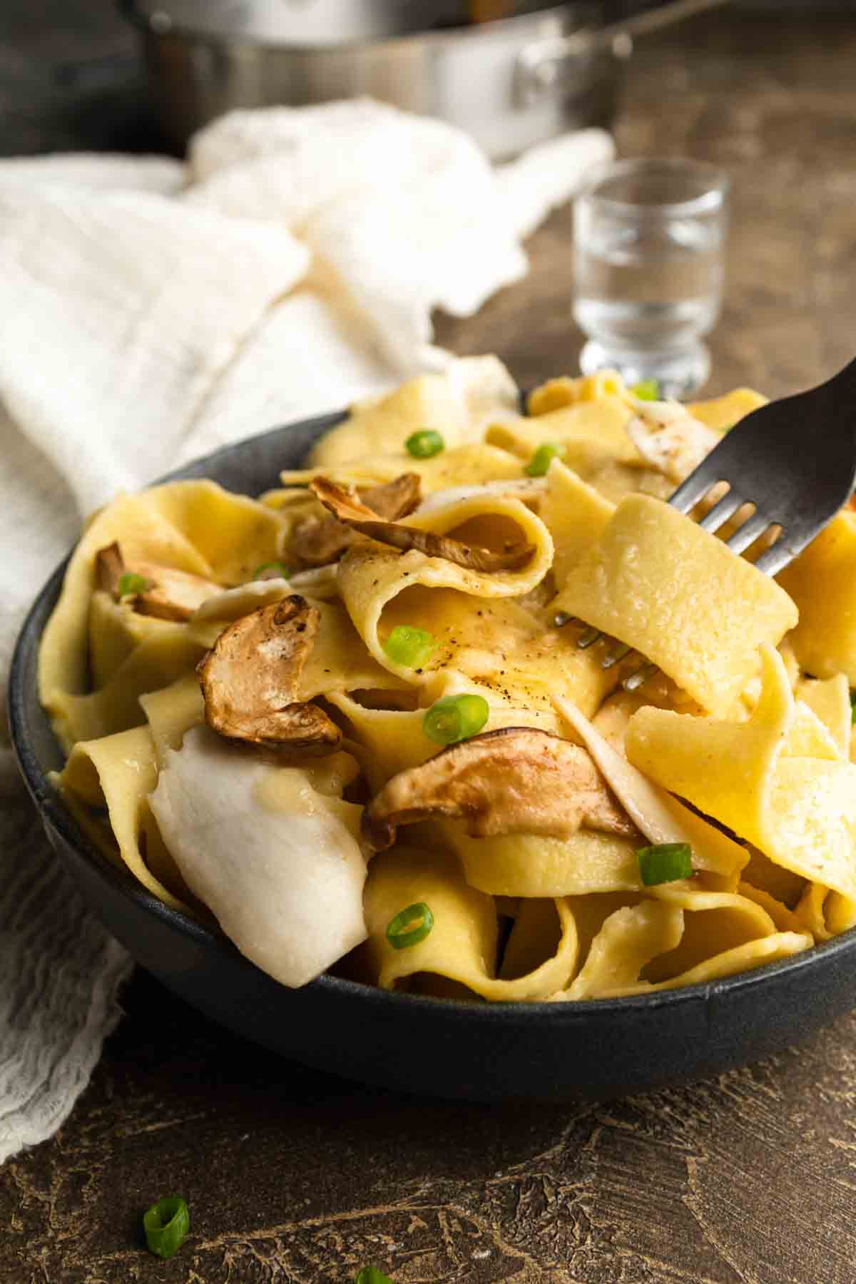 A fork twirling pappardelle in a bowl of matsutake pasta