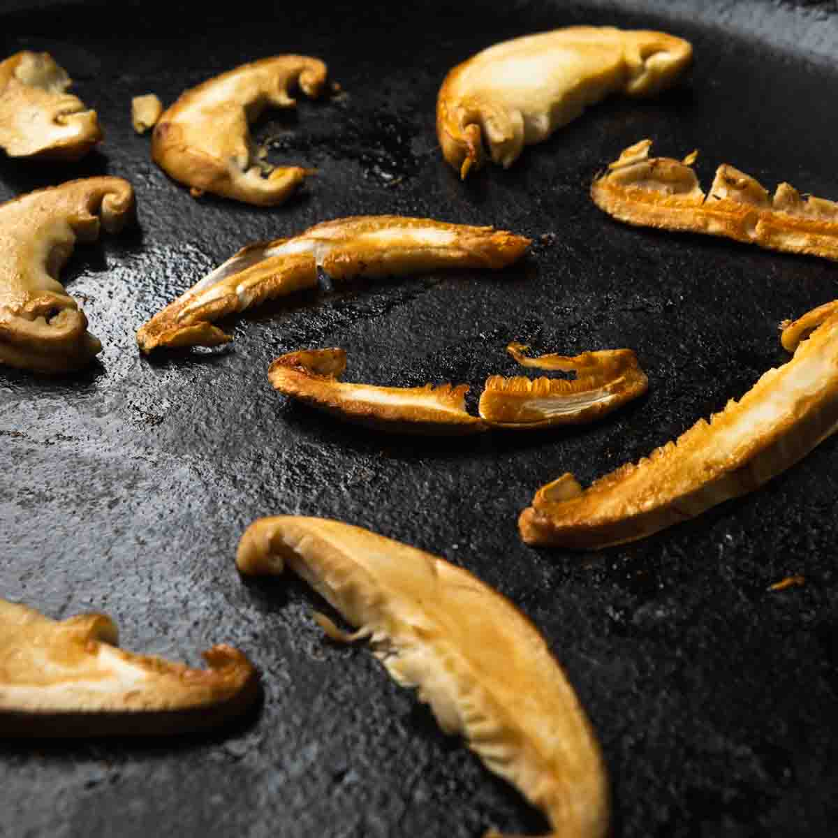 Sliced matsutake caps seared in a cast iron skillet