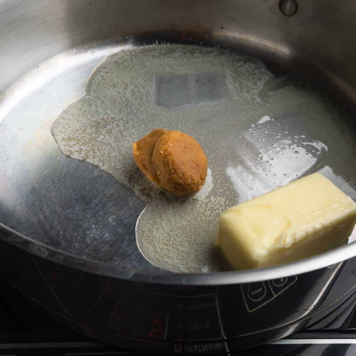 Butter melting in a skillet with a scoop of miso paste