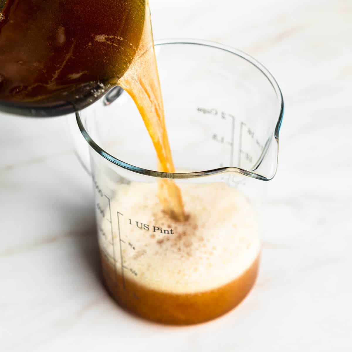 Pouring hot brown butter from the pan into a heat safe measuring cup