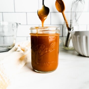 Caramel drizzling from a spoon into a mason jar