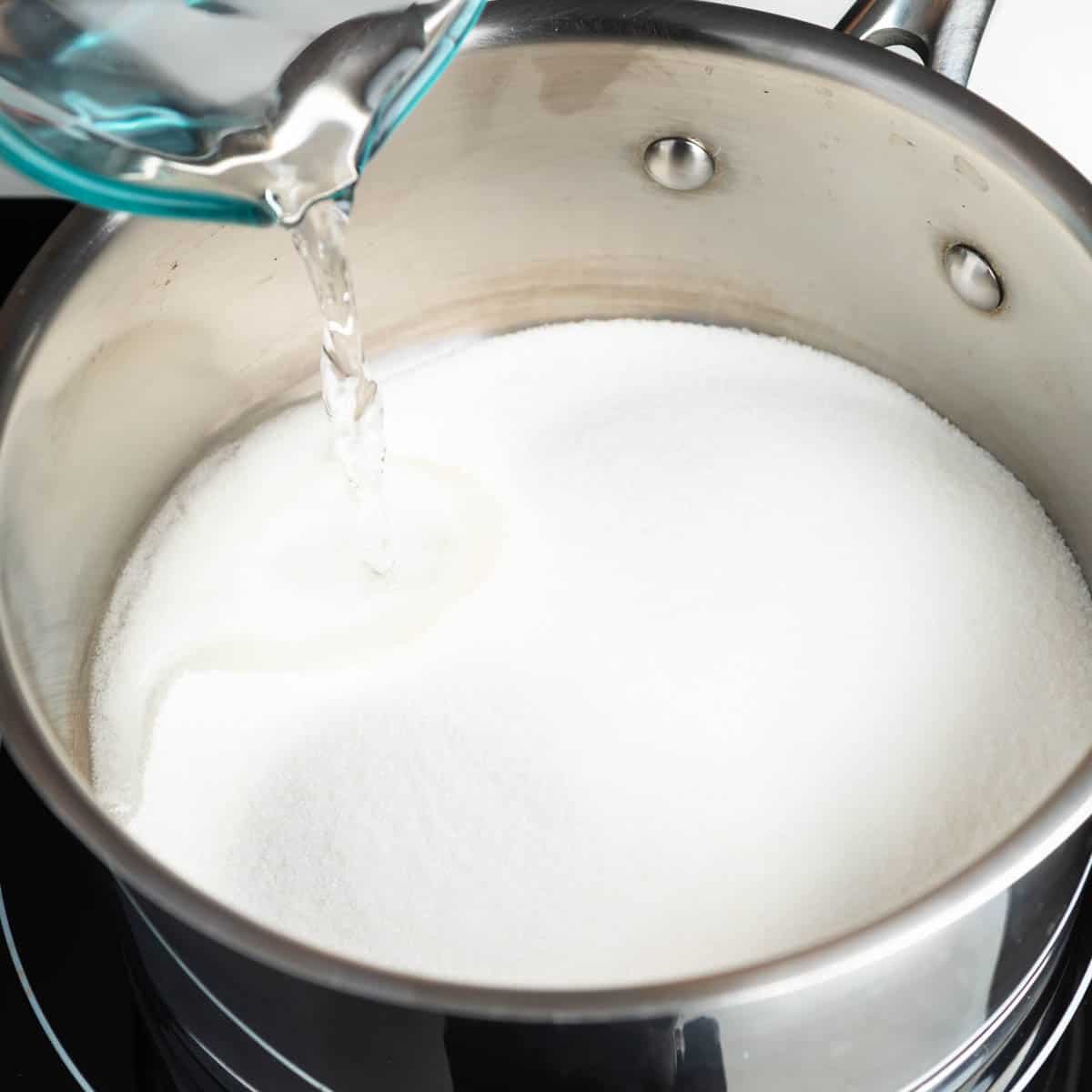 Pouring water into a pot filled with granulated sugar