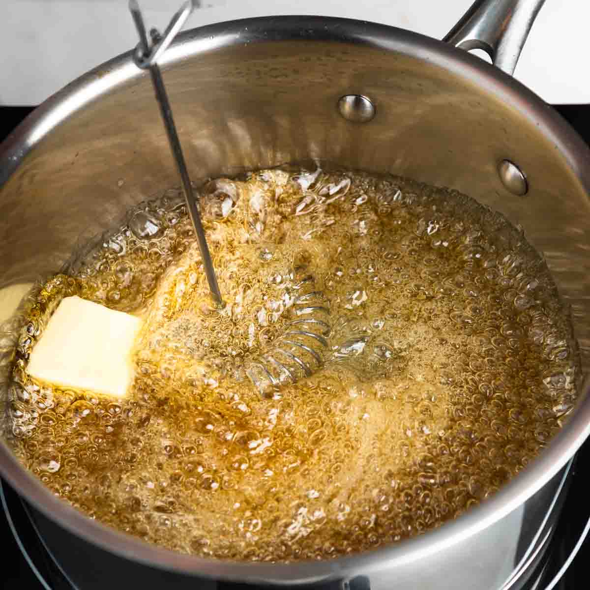 Whisking tablespoons of butter into the caramel syrup