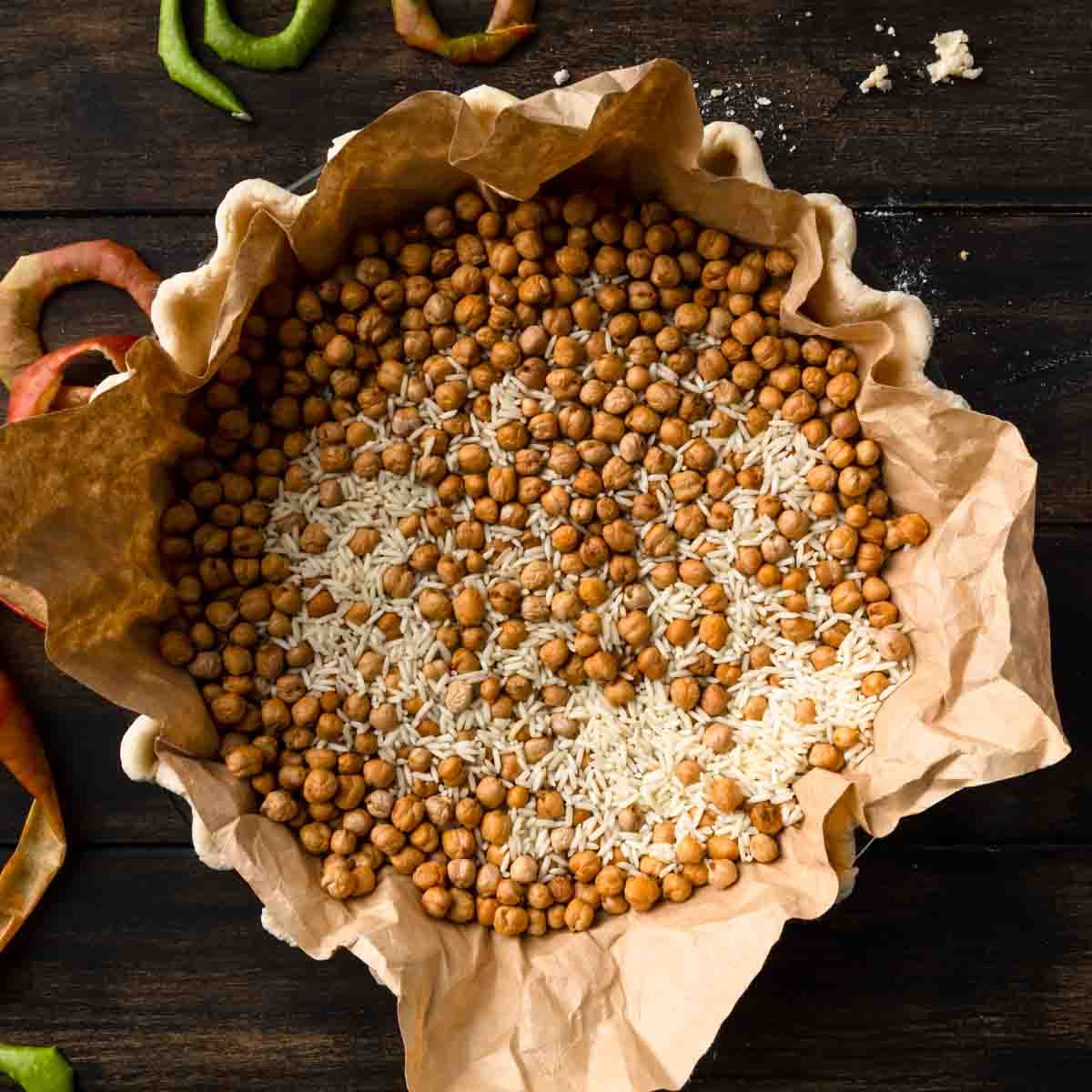 A raw pie crust lined with a coffee filter and filled with dried chickpeas and rice