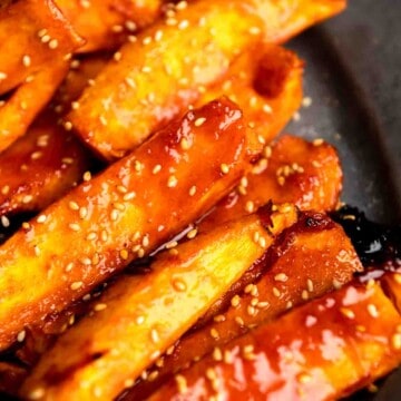 Spicy maple glazed pumpkin wedges piled on a grey plate.