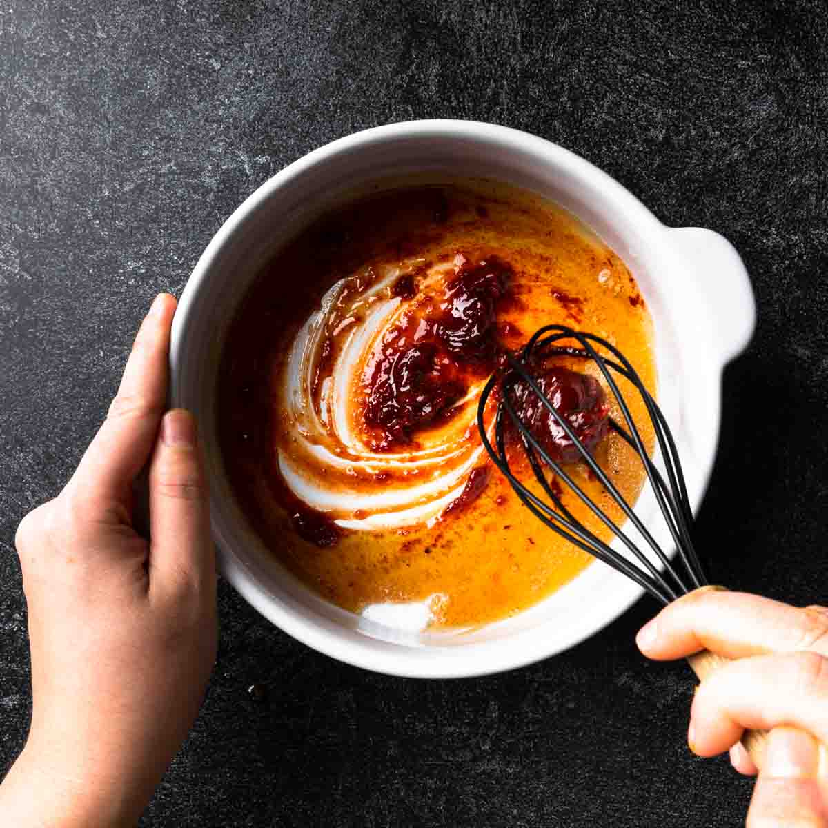 Whisking the maple gochujang and spices together in a big bowl.