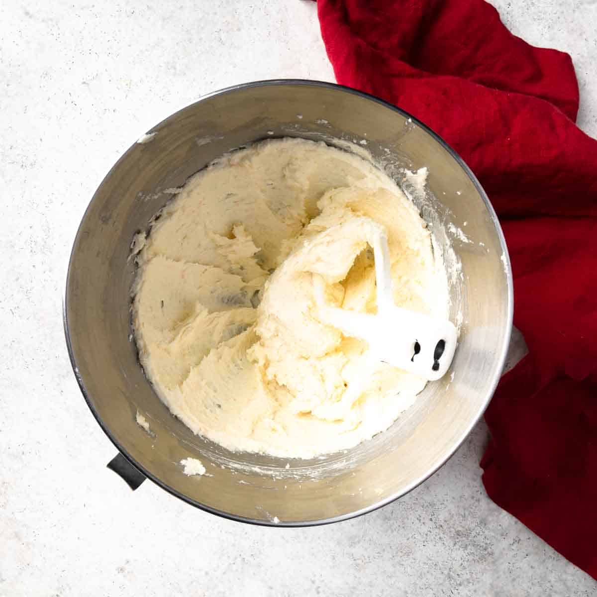 Fluffy butter and orange sugar creamed together in a stand mixer bowl.