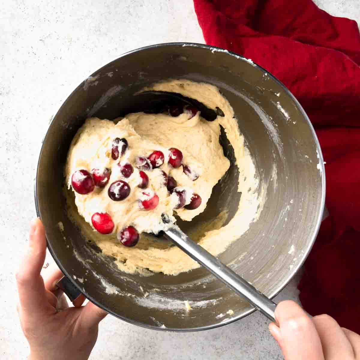Folding cranberries into cake batter with a rubber spatula. 