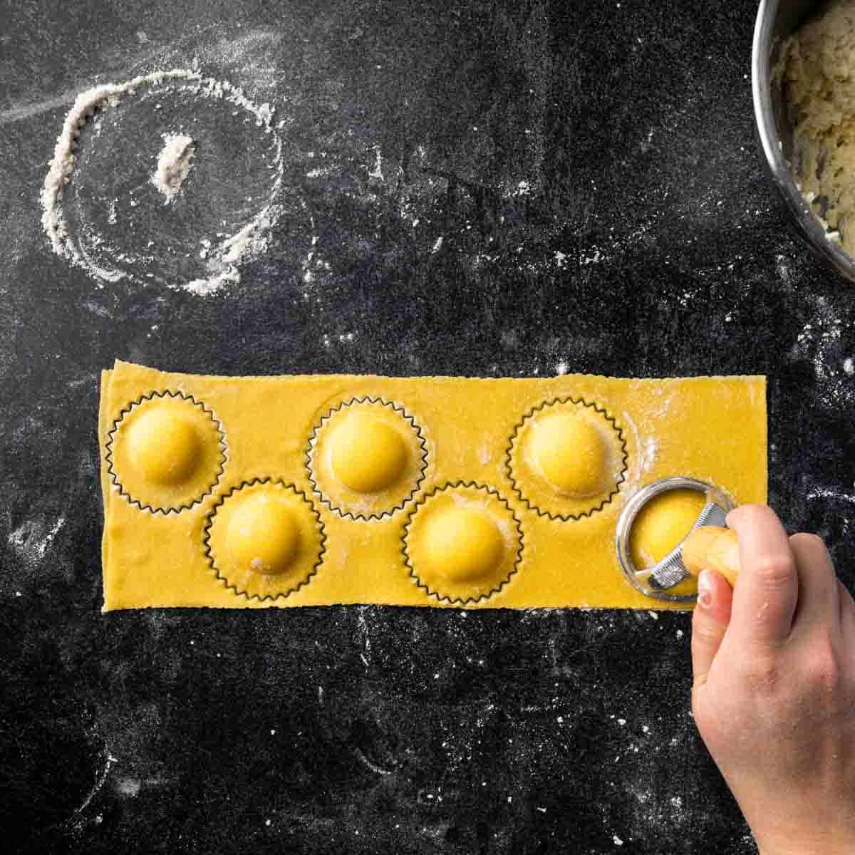 Using a ravioli stamp to punch out homemade ravioli.