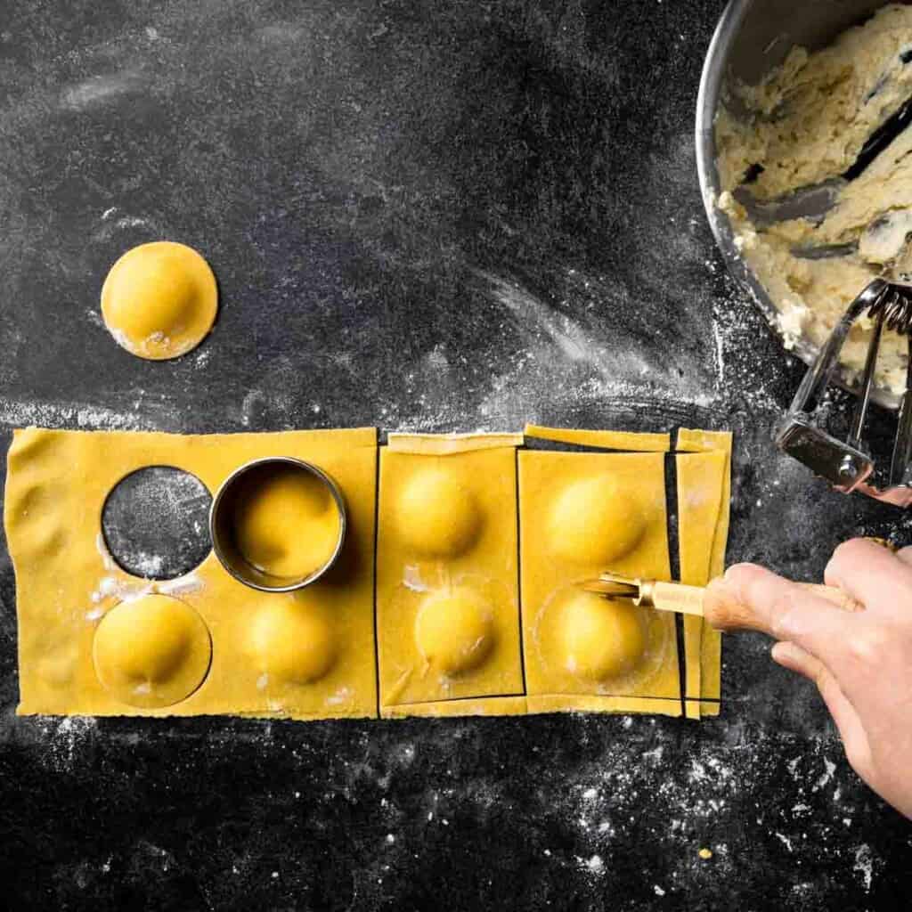 Cutting ravioli using cookie cutters and a brass pasta wheel.