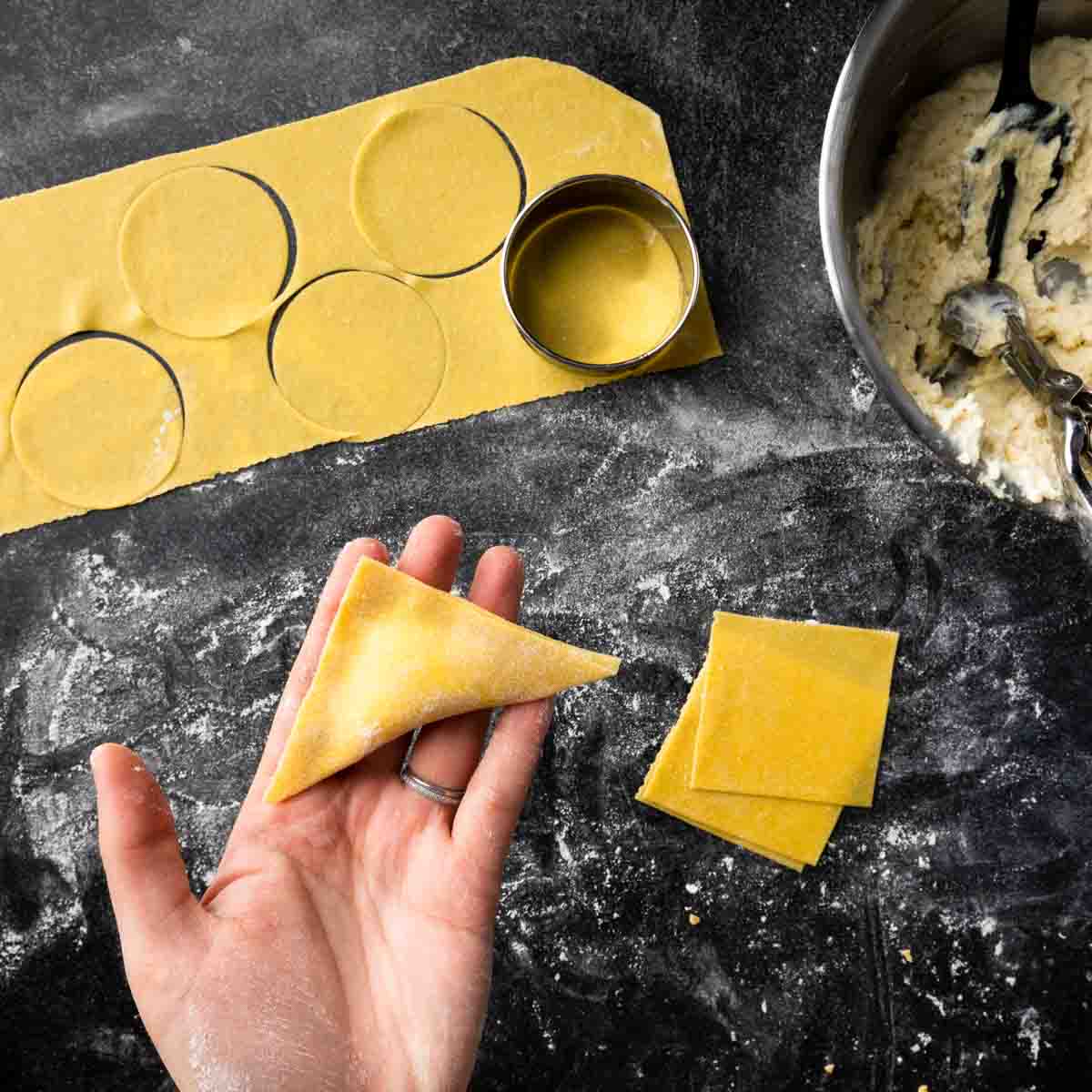 Holding up a triangular ravioli made using the wonton wrapper method.