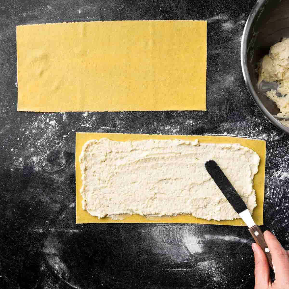 A fresh lasagna sheet covered in a thin layer of ricotta ravioli filling. 
