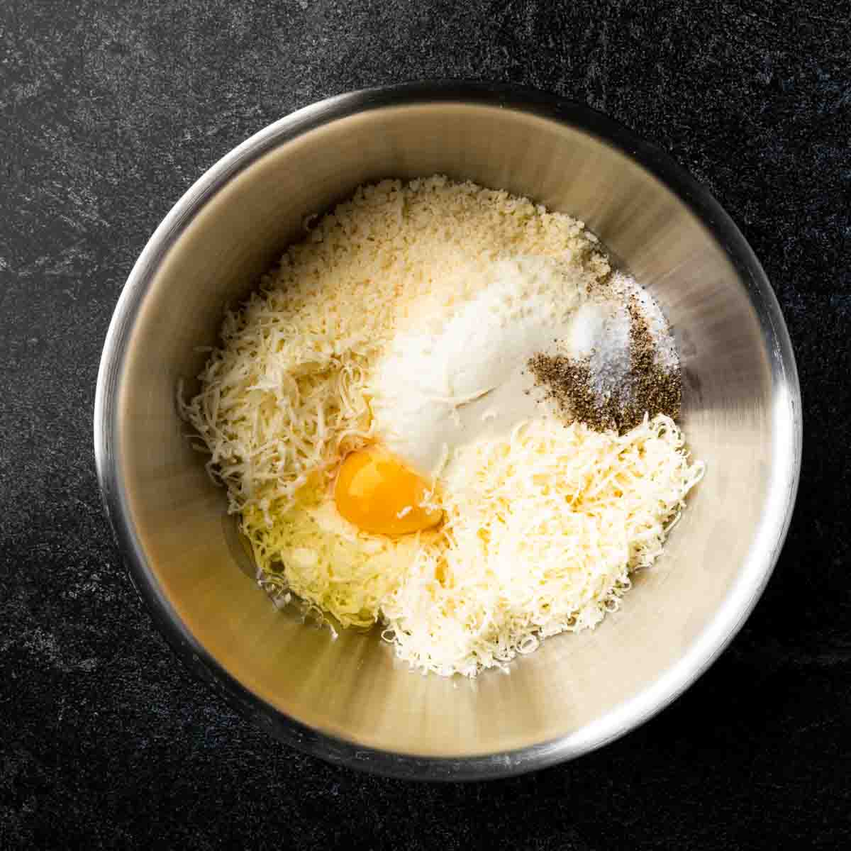 A bowl containing all of the ingredients for four cheese ravioli filling.