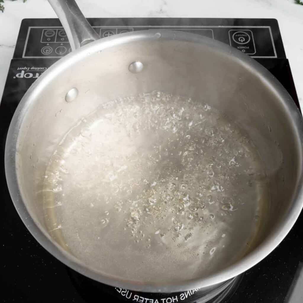 Simple syrup simmering in a stainless steel pot.