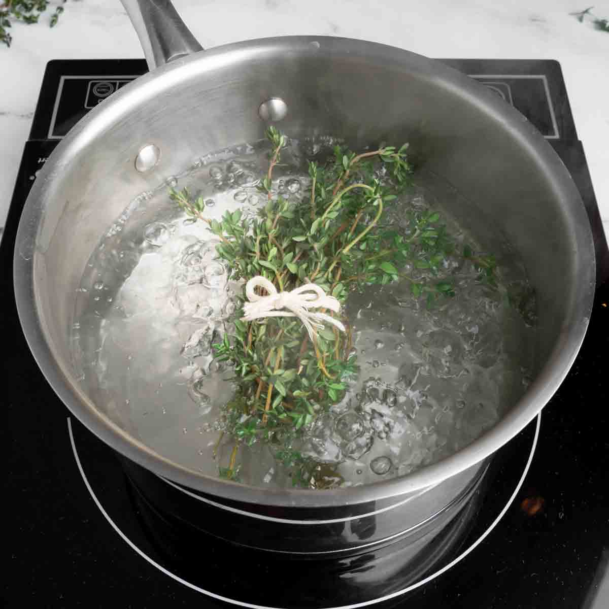 A bundle of thyme blanching in boiling water.