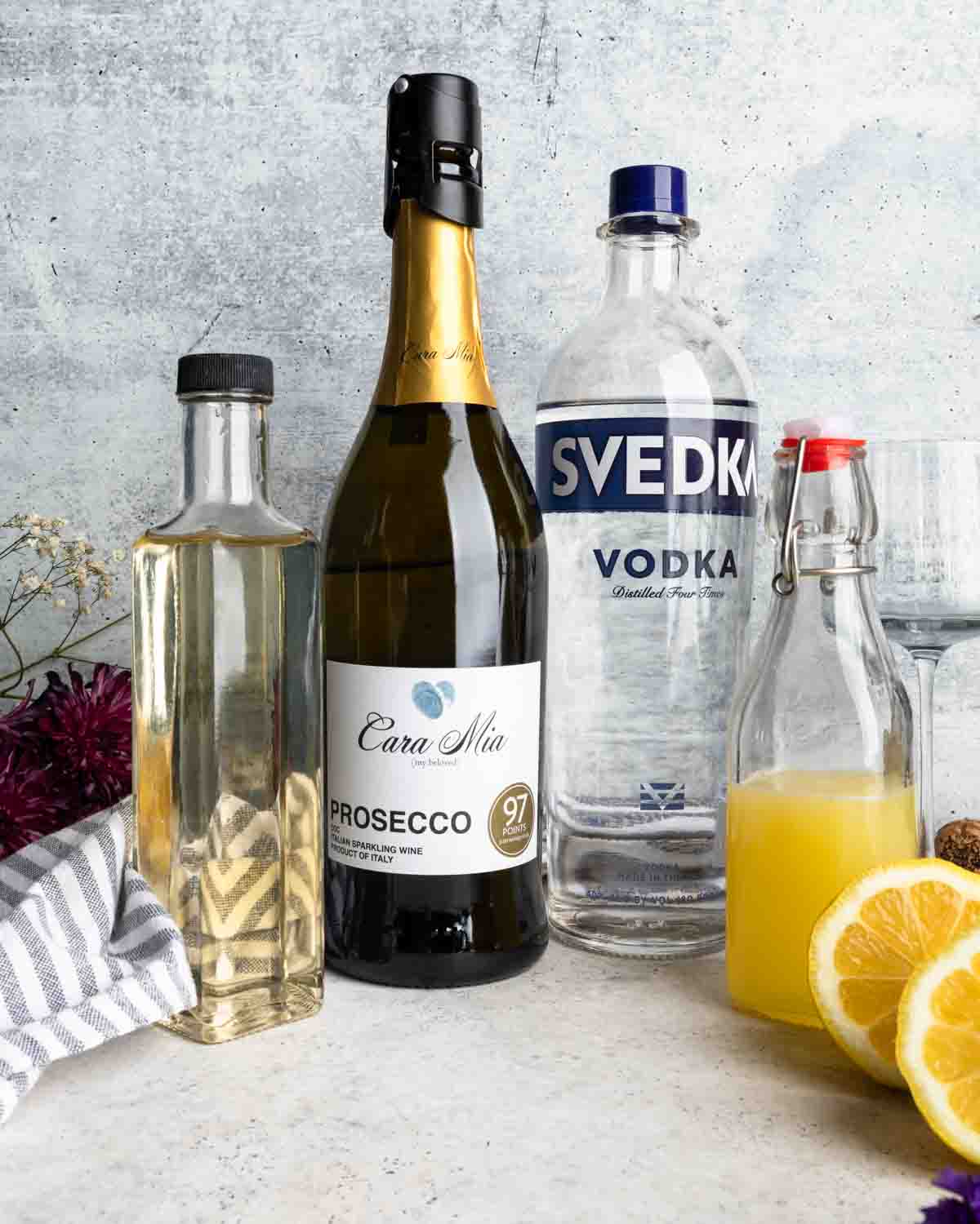 Ingredients for a French 76 including vodka, sparkling wine, lemon juice and simple syrup.