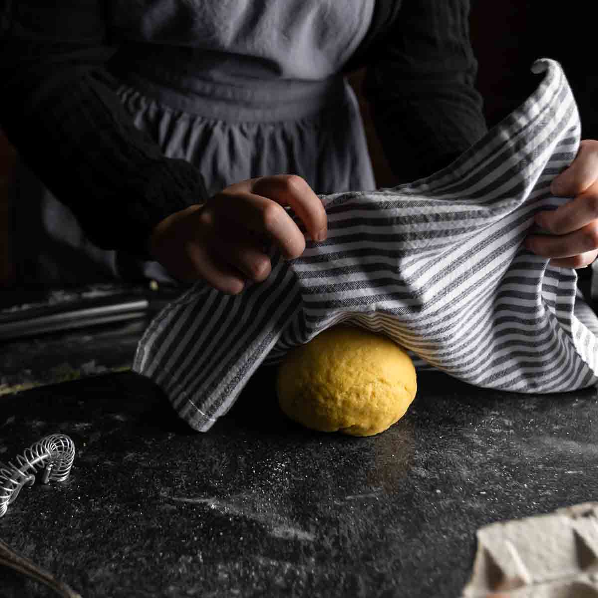 Covering a ball of pasta dough to rest after kneading.