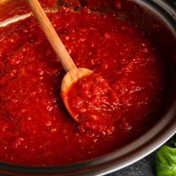 A wooden spoon in a pot of San Marzano tomato sauce.