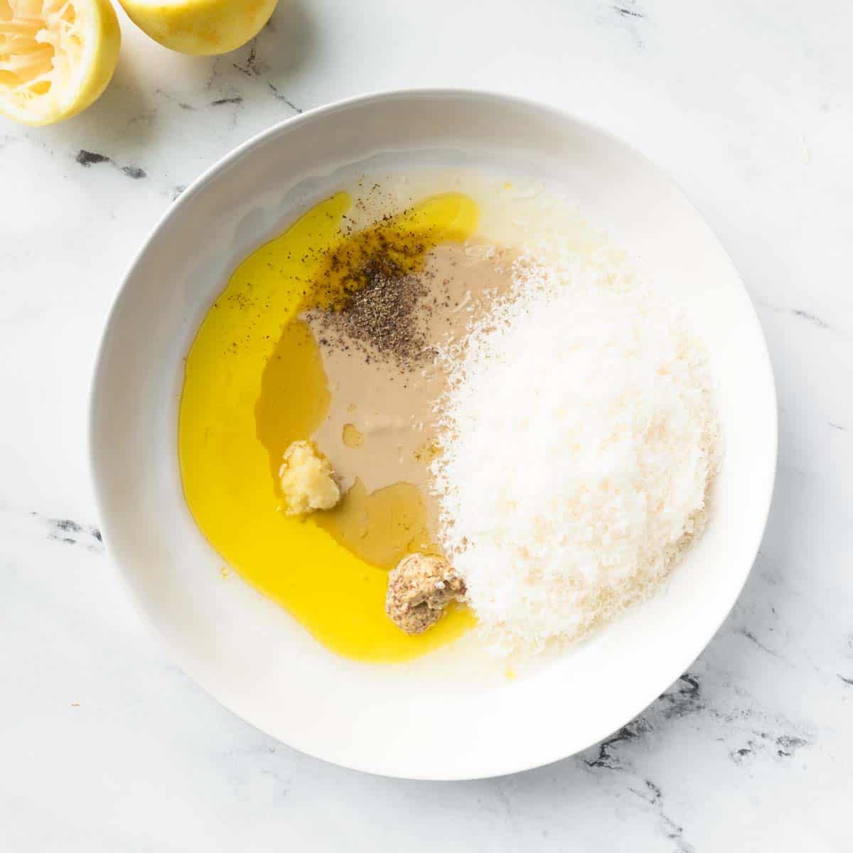 Ingredients for tahini Parmesan dressing in a white serving bowl.