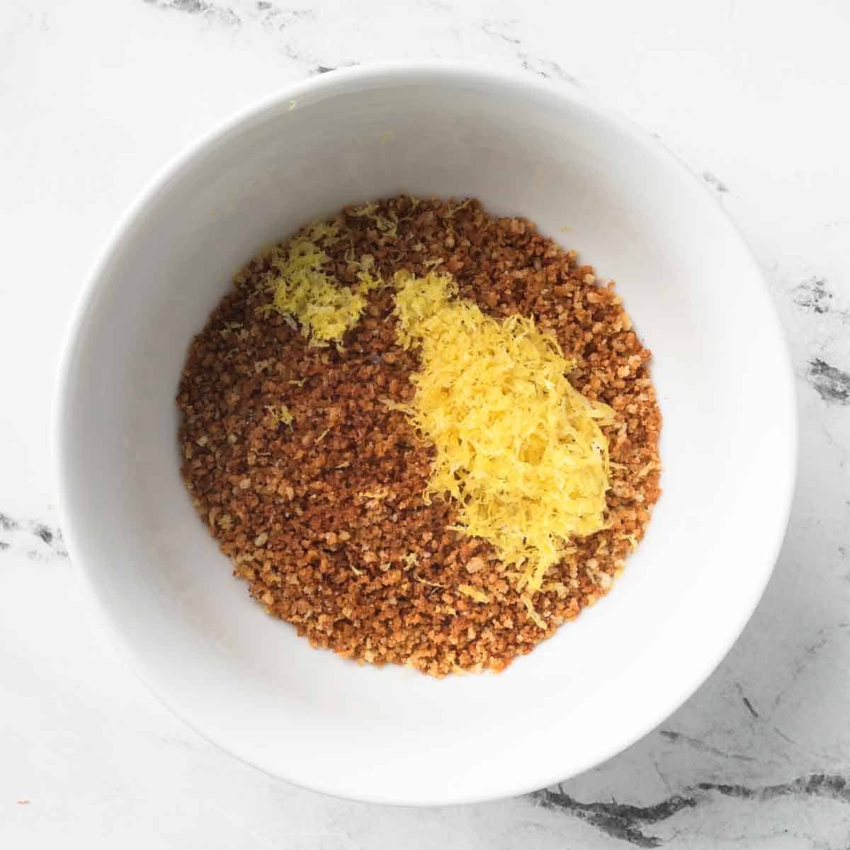 A bowl of toasted breadcrumbs topped with a pile of fresh lemon zest.
