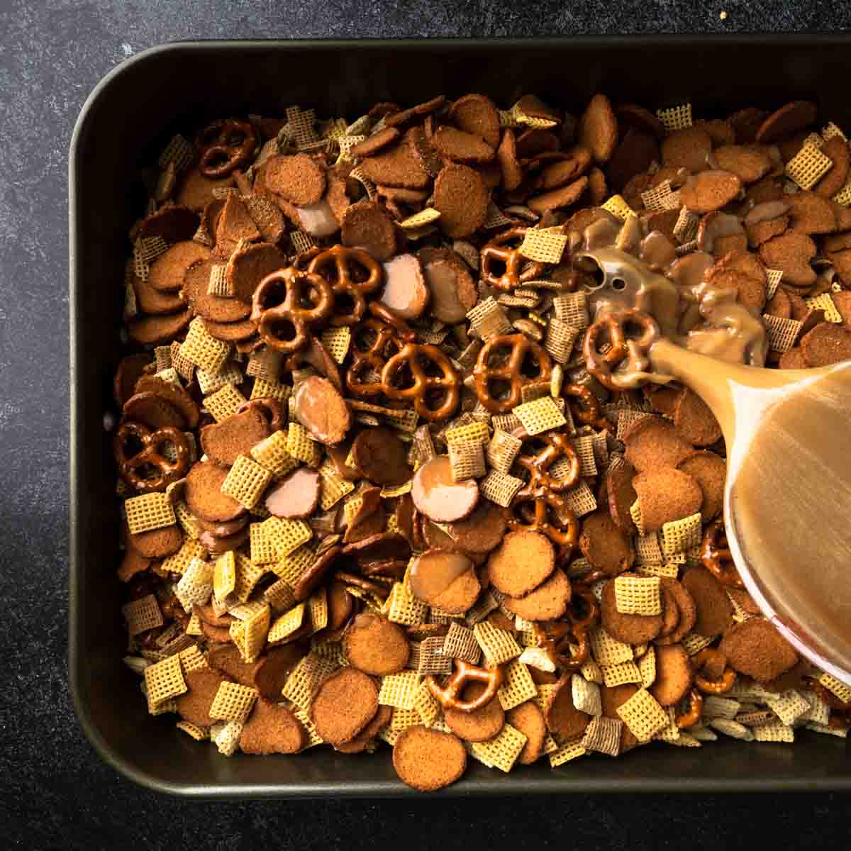 Pouring the melted butter and Worcestershire sauce mixture over the Chex mix. 
