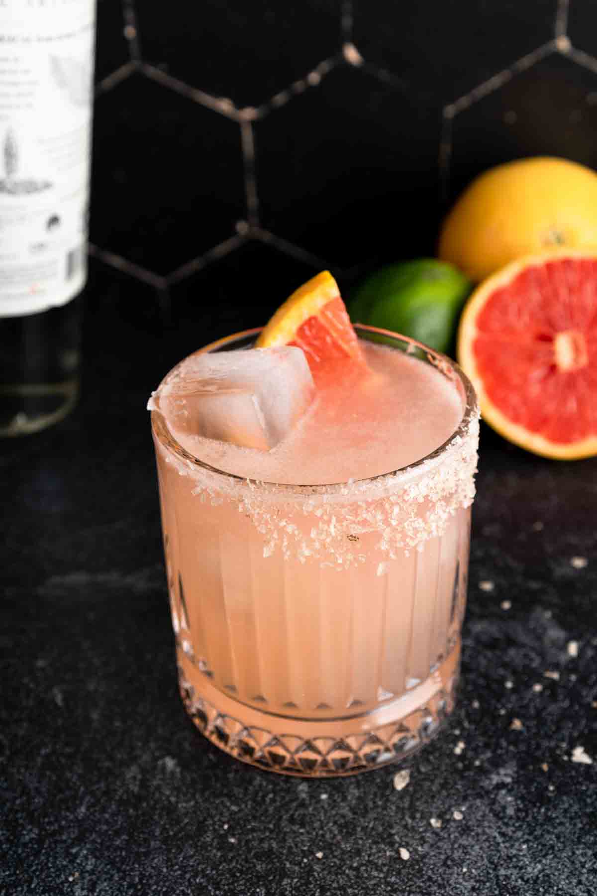 A mezcal paloma in a salted short glass with a grapefruit slice garnish.