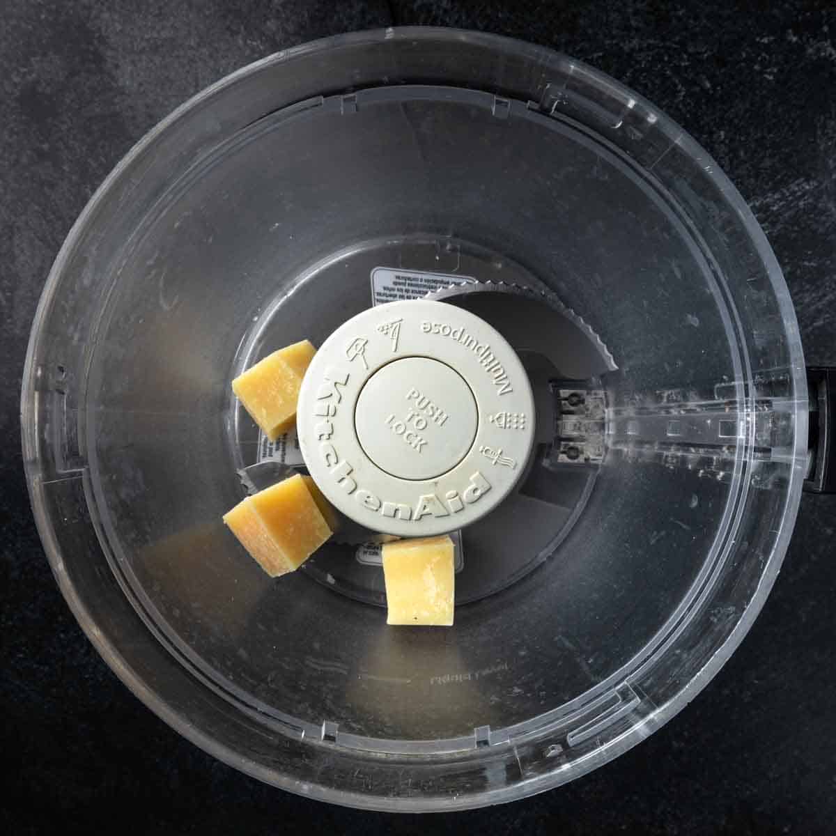 Cubes of Parmesan cheese in a food processor.
