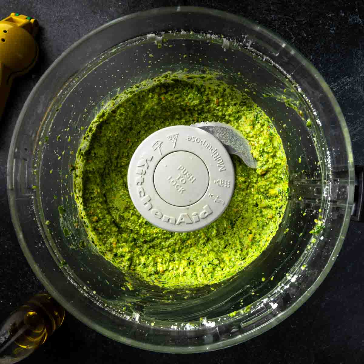 Fresh, bright green spinach and pistachio pesto sauce in a food processor. 