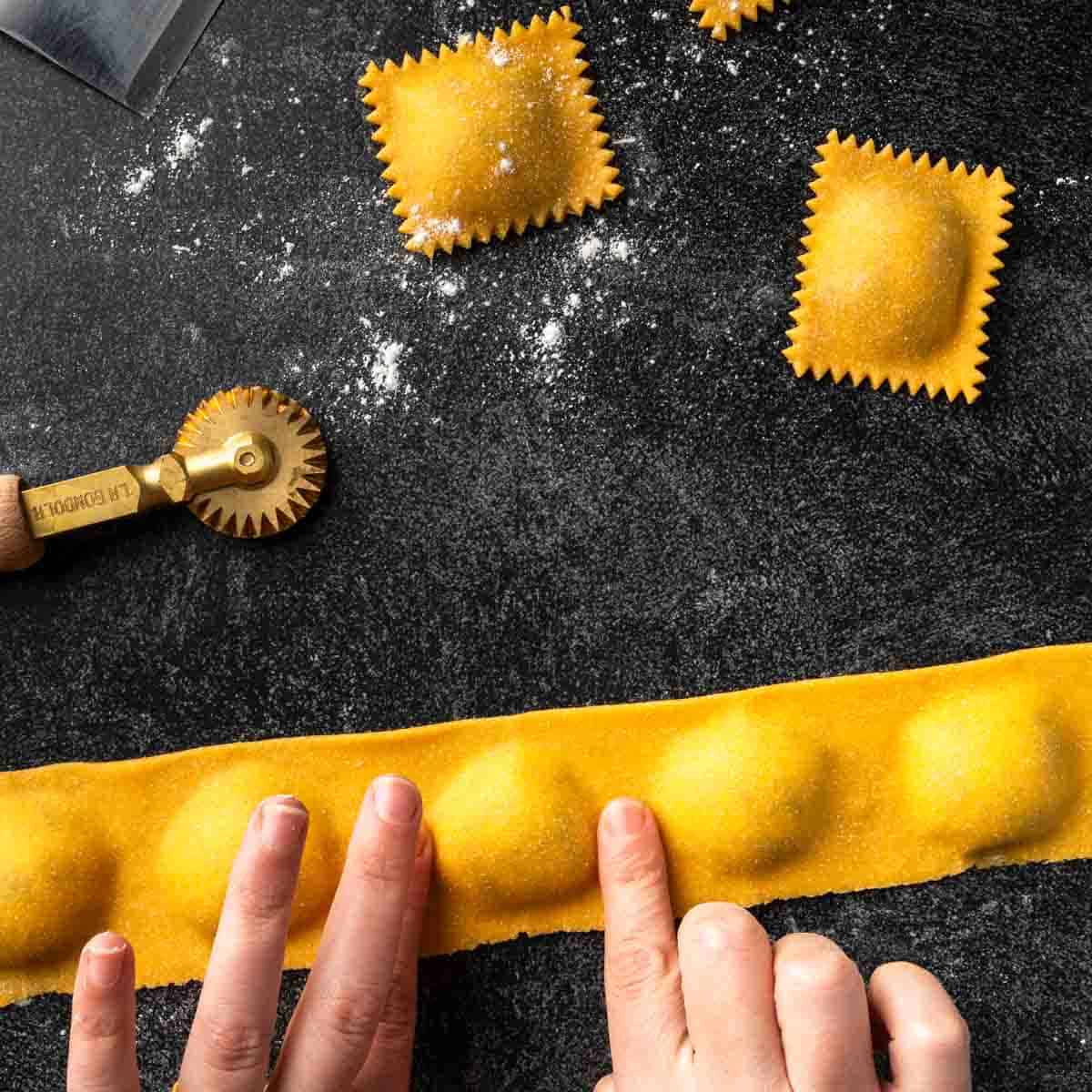 A row of ravioli being sealed by my fingertips before cutting into individual ravioli.