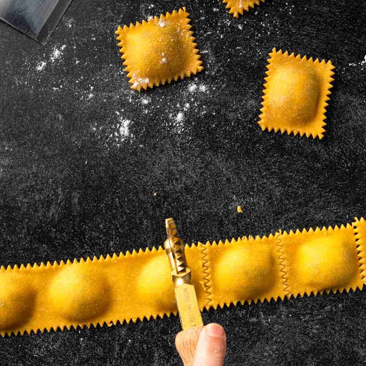 Using a fluted pasta wheel to cut ravioli into individual squares.