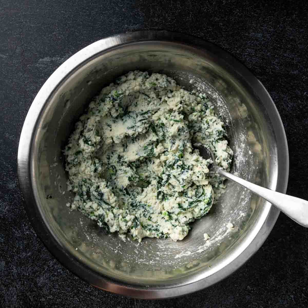A bowl full of spinach and ricotta ravioli filling. 