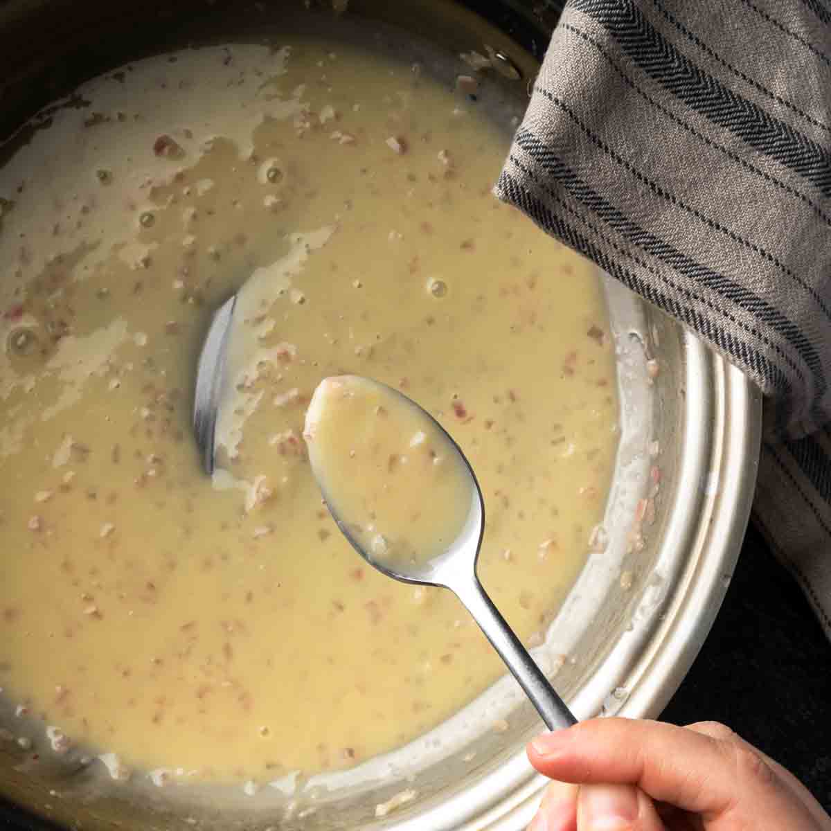 A creamy, glossy butter sauce on a spoon speckled with bits of shallot.